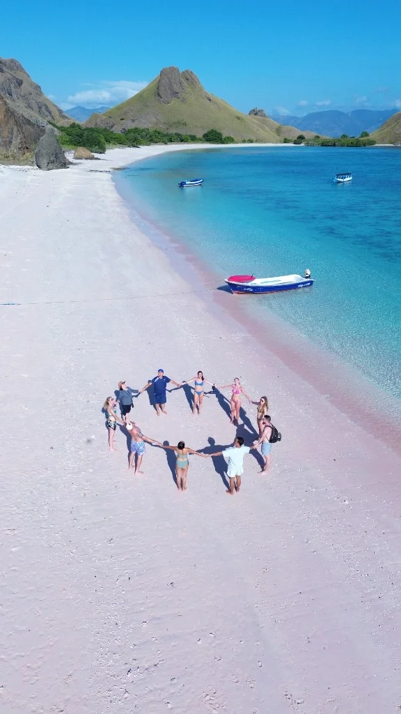 Aerial drone shot of tourists forming a circle on the iconic Pink Beach in Komodo National Park