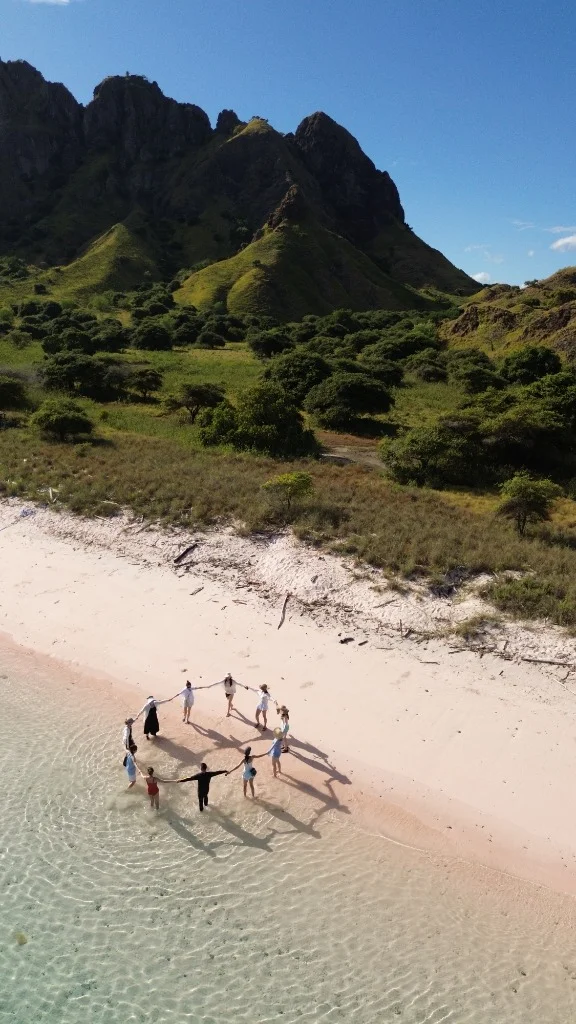 Drone view of travelers holding hands in the crystal clear turquoise waters of Labuan Bajo